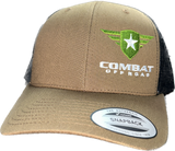 A tan and black trucker-style snapback hat with the Combat Off Road logo embroidered on the front. The logo features a green shield with a white star and winged accents, accompanied by the text "Combat Off Road" in bold white lettering. The front panel is tan, and the mesh back is black, with a sticker on the brim that reads "The Authentic Snapback". The hat has a curved brim for a comfortable fit.