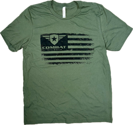 A green t-shirt featuring a distressed black design of the Combat Off Road logo integrated into a stylized American flag. The logo, placed in the top left corner of the flag, includes a shield with a star and winged accents, accompanied by the text "Combat Off Road" in bold black letters. The shirt has a classic crewneck and short sleeves, offering a casual and rugged look.